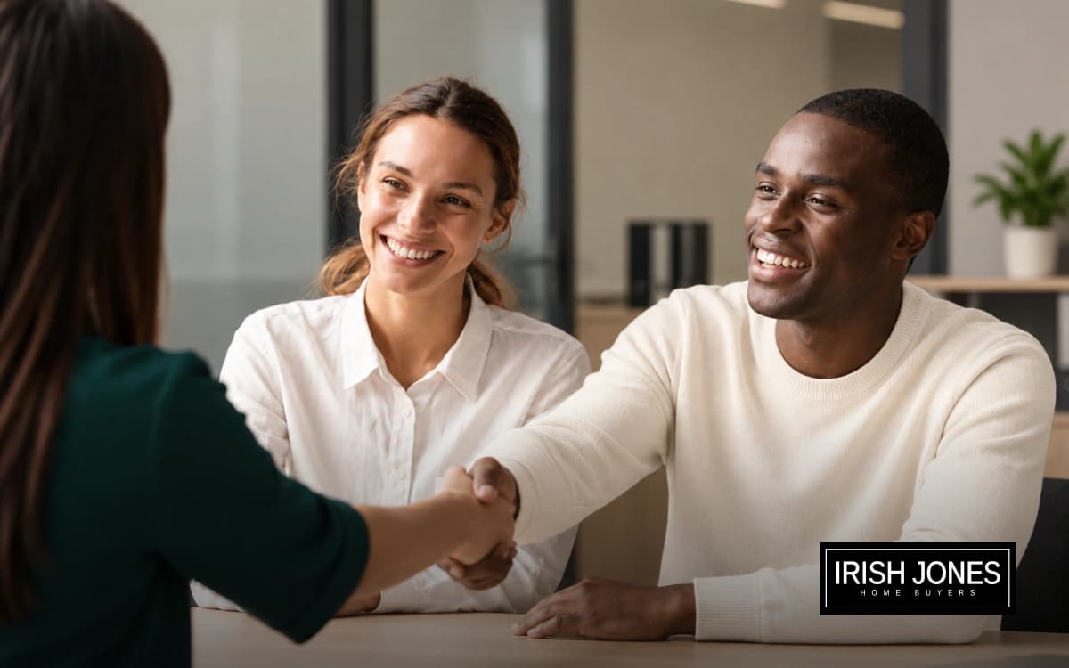 A couple shaking hands with a buyer across a table
